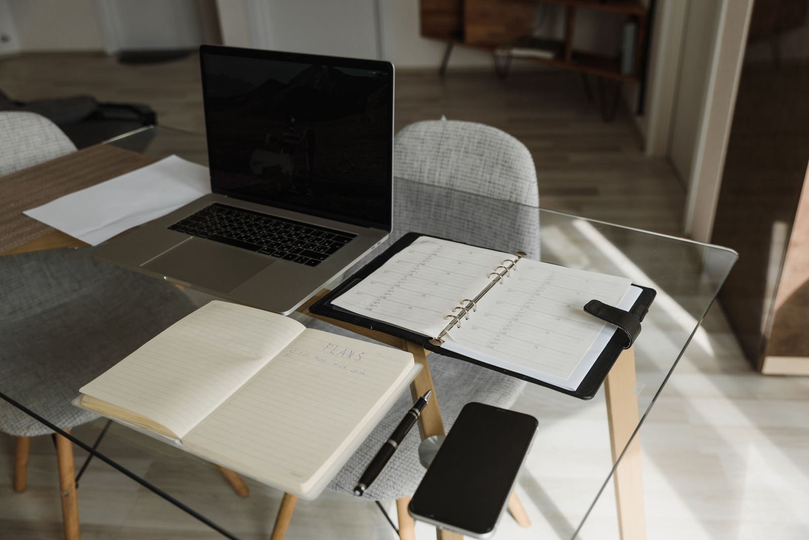 A laptop, notebook and planner arranged on a desk