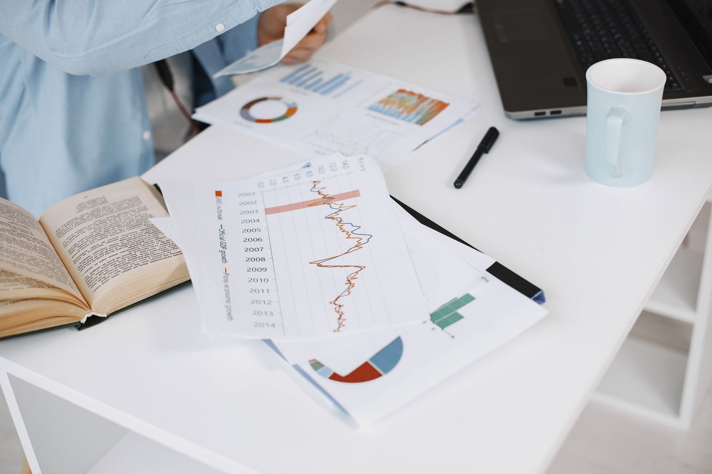 Charts and research notes beside a laptop on a desk